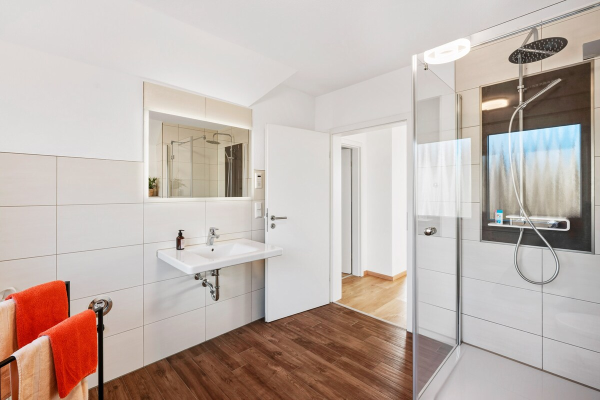 Modernes Badezimmer mit großem Spiegel und gläserner Duschkabine