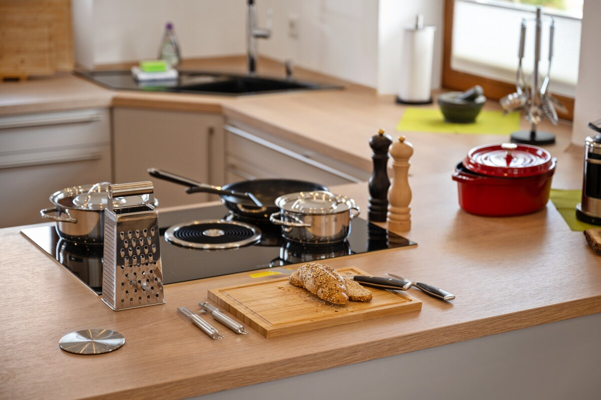 Helle Küchenzeile mit Spülbecken, Induktionskochfeld und Kaffeemaschine.