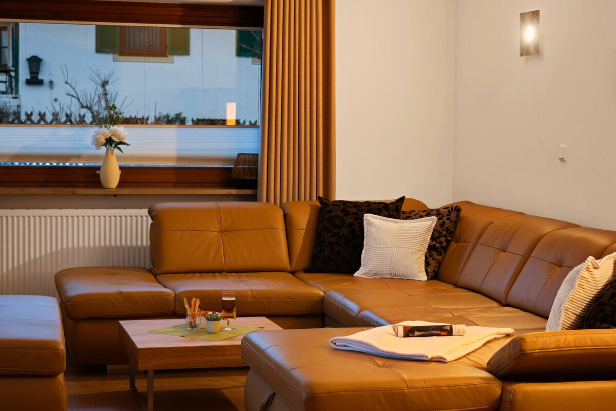 Gemütlicher Sitzbereich im Wohnzimmer mit einem modernen, camelfarbenen Ledersofa.